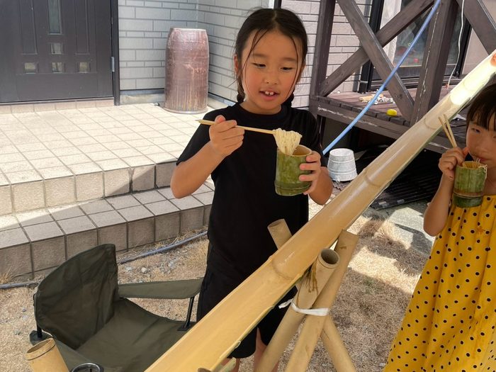 竹樋から流しそうめんをすくう子どもたち